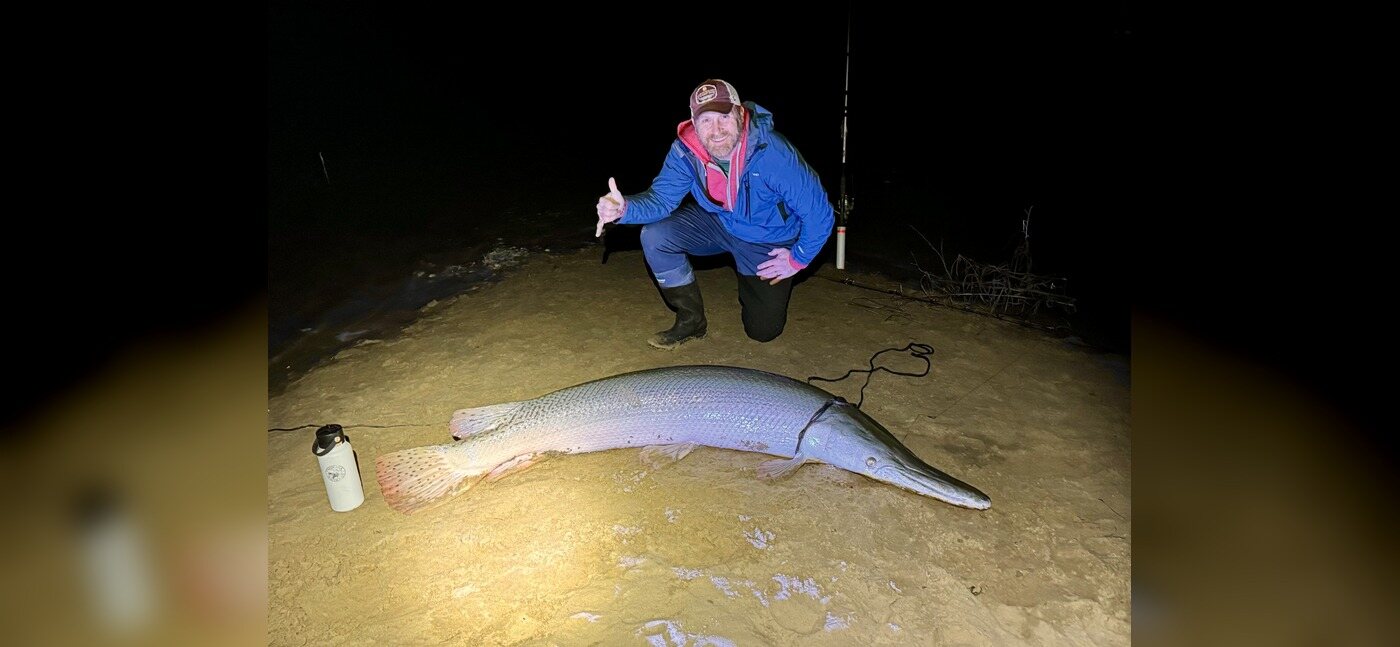 Angler beside a large alligator gar caught at night