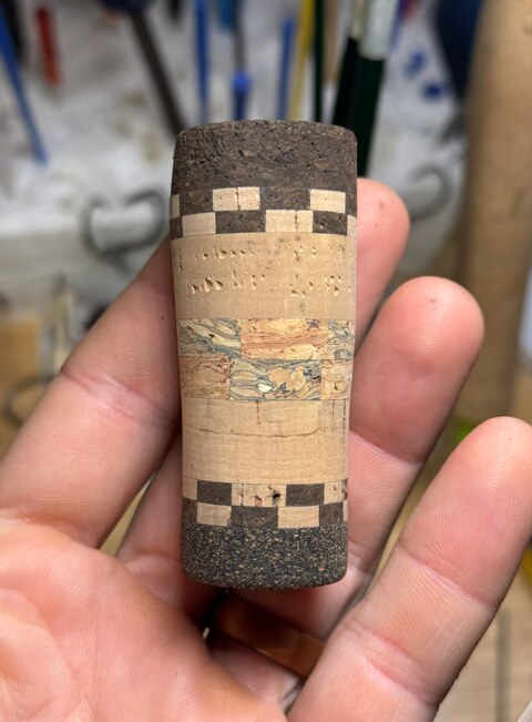 Close-up of a handcrafted cork fishing rod grip with decorative checkerboard accents
