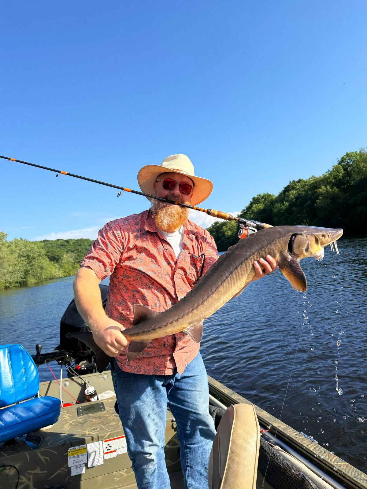 Angler holding a large sturgeon caught on a custom fishing rod